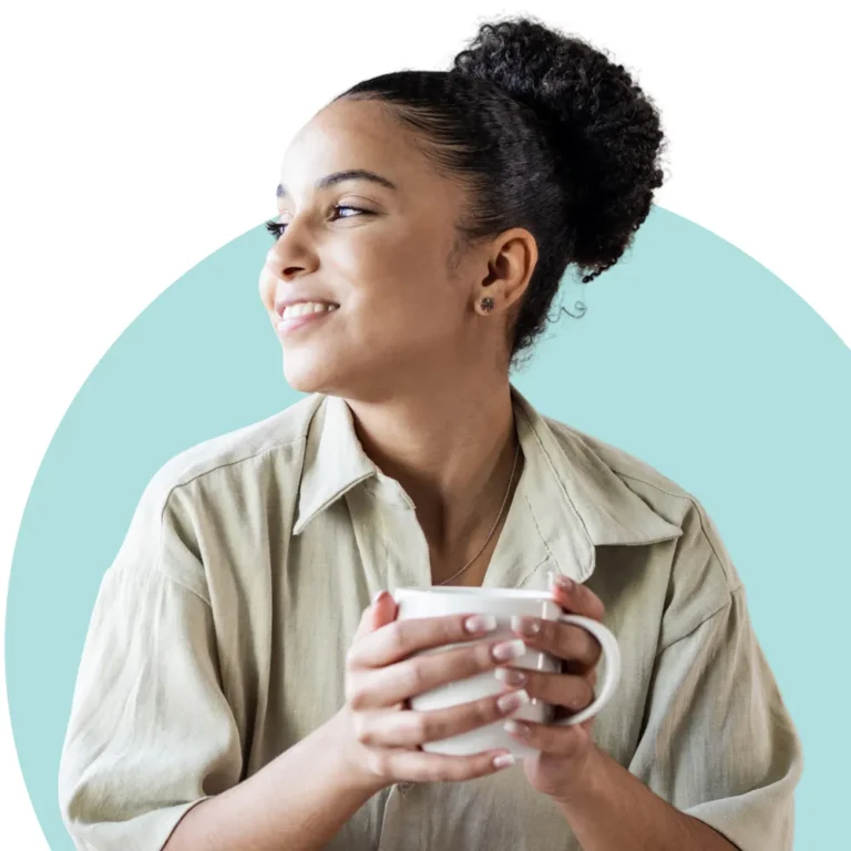 Turnwell Mental Health image featuring a person with curly hair tied up in a bun, holding a white mug with both hands, wearing a light-colored shirt, and looking to the side. The background features a light blue circular shape.