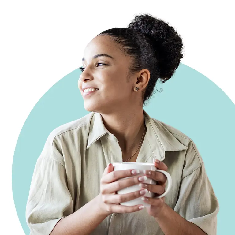 Turnwell Mental Health image featuring a person with curly hair tied up in a bun, holding a white mug with both hands, wearing a light-colored shirt, and looking to the side. The background features a light blue circular shape.