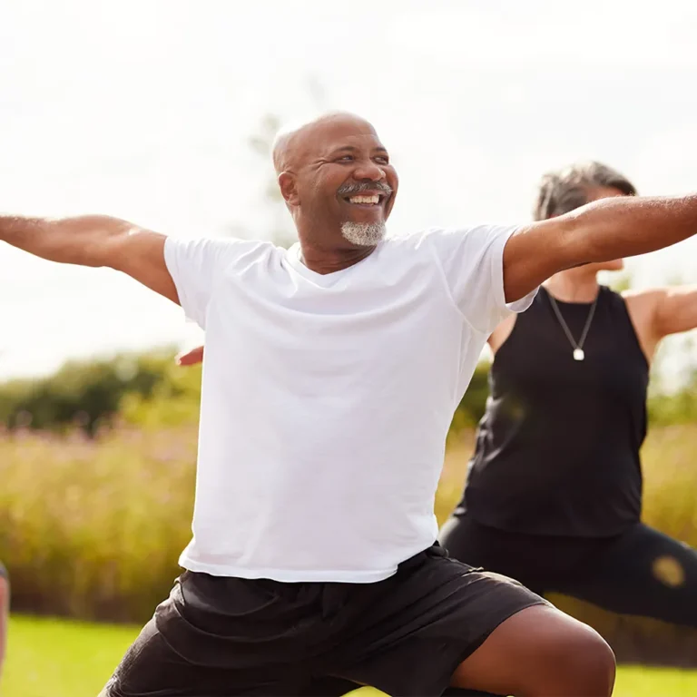 Happy Black man with arms outstretched celebrating outdoors during exercise, embodying wellness and healthy living for National Wellness Month