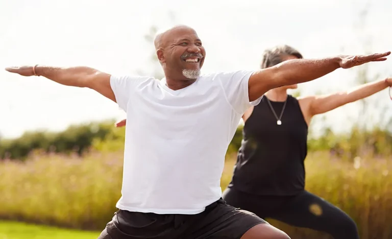 Happy Black man with arms outstretched celebrating outdoors during exercise, embodying wellness and healthy living for National Wellness Month