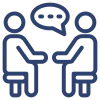 Group psychotherapy icon featuring two simplified human figures sitting on chairs facing each other with a speech bubble containing three dots between them, symbolizing communication and therapeutic conversation in a group setting.